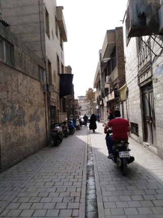 A narrow old alley in which people are commuting